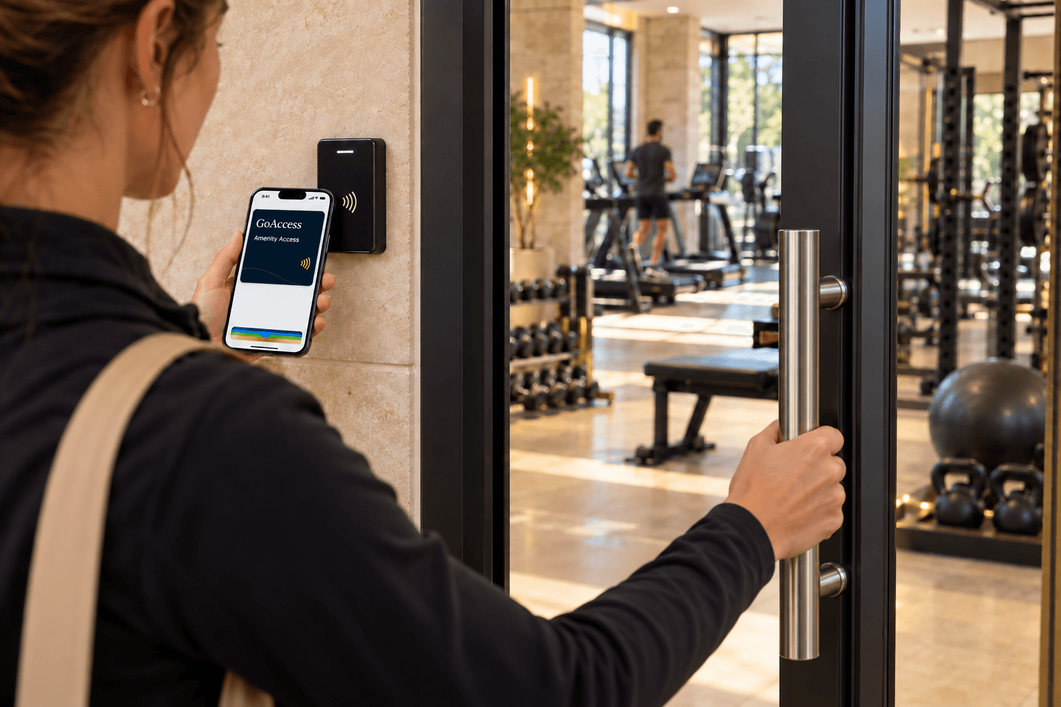 A resident holds a navy GoAccess pass in Apple Wallet near a door reader while opening a community fitness-center door