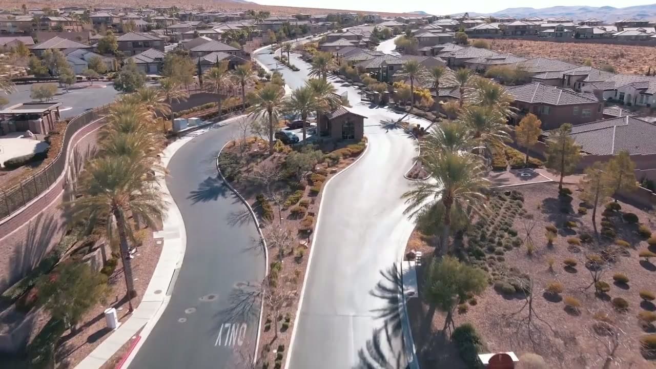 Aerial view of a gated residential entrance and the neighborhood beyond